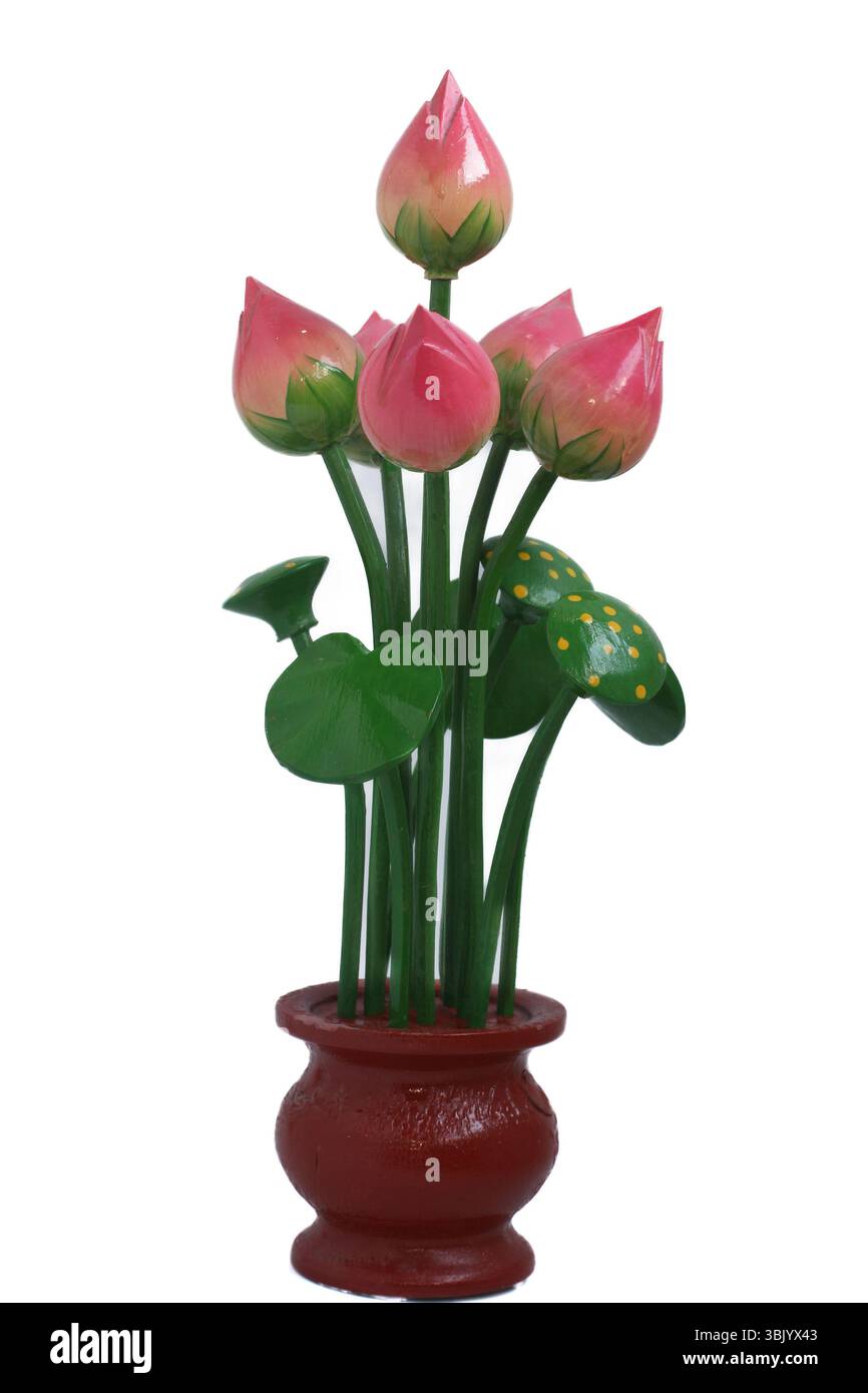 Handgefertigte hölzerne Lotusblüten in leuchtendem Rosa mit grünen Blättern in einem braunen Topf auf weißem Hintergrund. Wunderschönes handwerkliches Wohndekor. Stockfoto