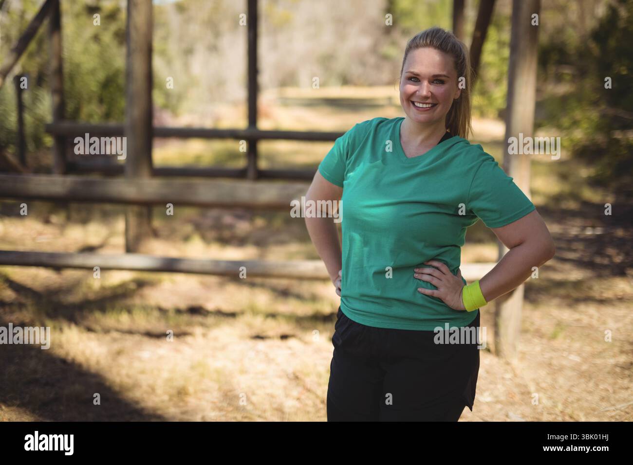 Rustikaler Holzzaun, der sich über sonnendurchfluteten Waldweg mit trockenem Gras und Blättern erstreckt, Kopierraum Stockfoto