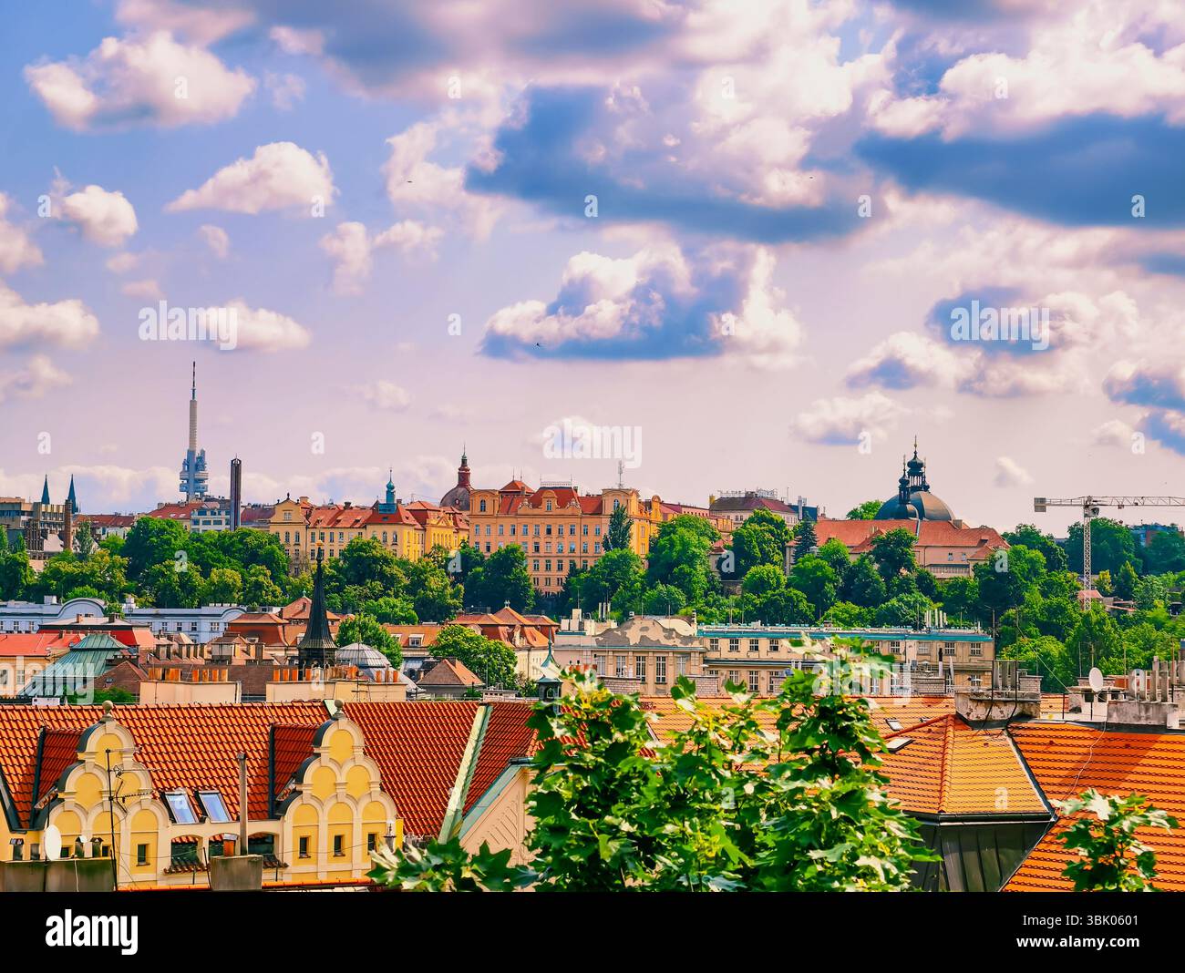Prags Skyline: Ein fesselnder Blick auf die rot gekachelten Dächer und die historische Architektur, gebadet in leuchtend blauem Himmel mit flauschigen Wolken, die den einzigartigen Charme der Stadt zum Ausdruck bringen. Stock-Foto Stockfoto