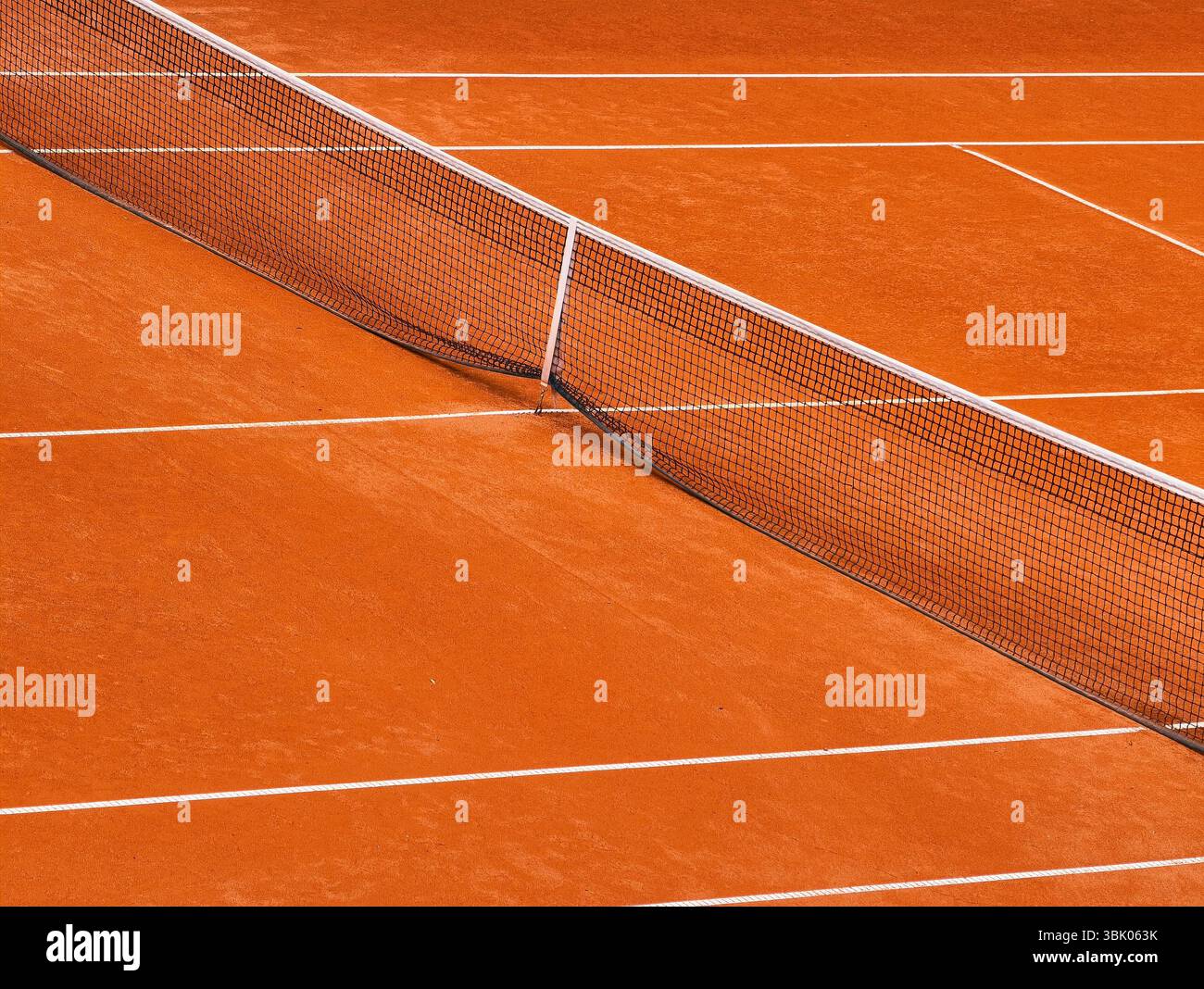 Lebendiger Tennisplatz aus Ton, in warmes Sonnenlicht getaucht, mit einem perfekt straffen Netz, Einer beeindruckenden Szene aus athletischer Eleganz und natürlicher Schönheit, ideal für Sportbegeisterte und zeitlosen Sportcharme Stockfoto