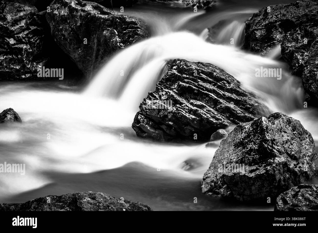 Langzeitaufnahme eines schnellen Gebirgsflusses in Schwarz-weiß Stockfoto