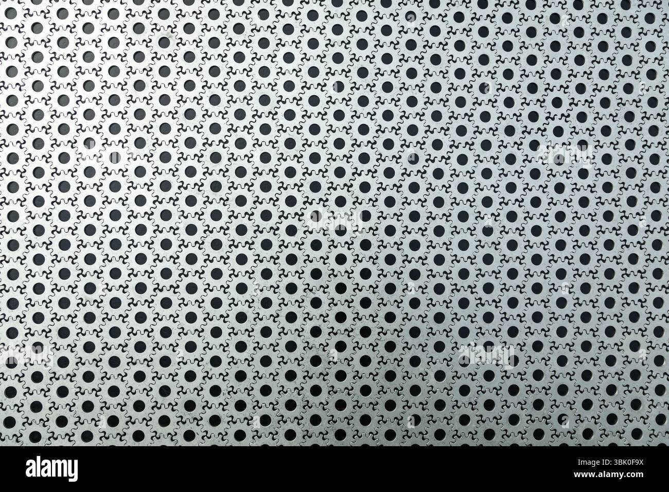 Zahnradhintergrund. Eine große Anzahl von Stahlzahnrädern, die auf schwarzem Hintergrund miteinander verbunden sind. Stockfoto