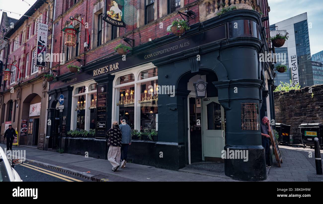 NEWCASTLE, Großbritannien - 13. JUNI 2025 - Paar spazieren in der Nähe von Rosie's Bar, einem traditionellen Pub in Newcastle upon Tyne, England, mit City Gate Gebäude im bac Stockfoto