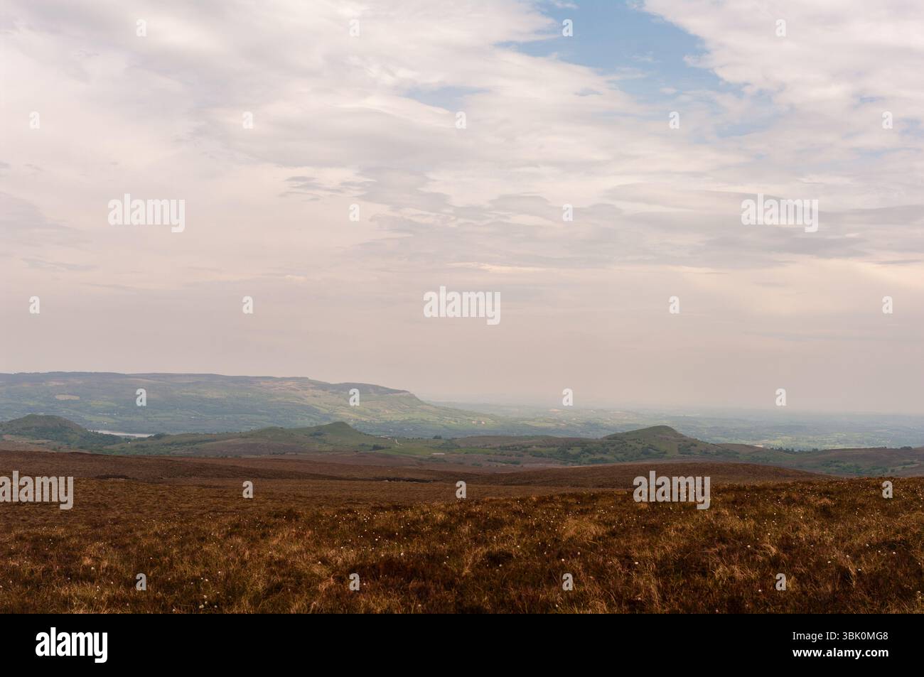 Ein riesiges, leeres Feld mit einem bewölkten Himmel im Hintergrund. Der Himmel ist eine Mischung aus Blau und weiß, mit einigen Wolken verstreut. Das Feld ist barre Stockfoto
