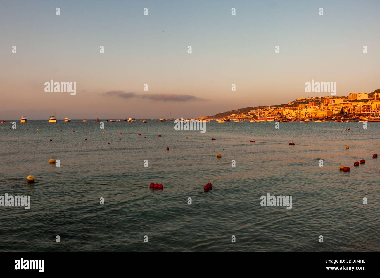 Ein ruhiges Meer mit ein paar Booten im Wasser. Der Himmel hat eine wunderschöne orange Farbe Stockfoto Ein ruhiges Meer mit ein paar Booten im Wasser. Der Himmel hat eine wunderschöne orange Farbe Stockfoto