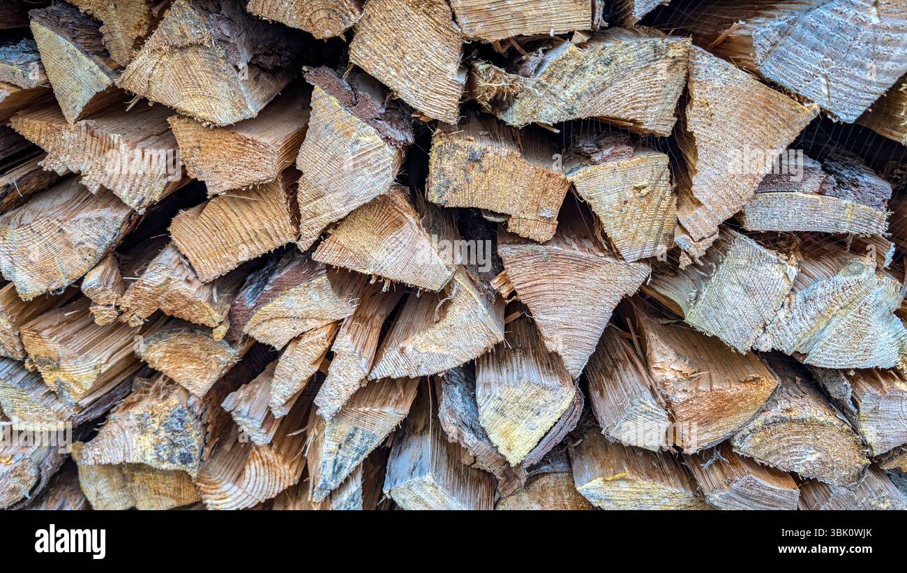Detaillierte Ansicht von geteilten Stämmen, die auf einem Holzstapel gestapelt sind, mit rauer Holzmaserung, geschnittenen Oberflächen und rustikaler Textur. Stockfoto