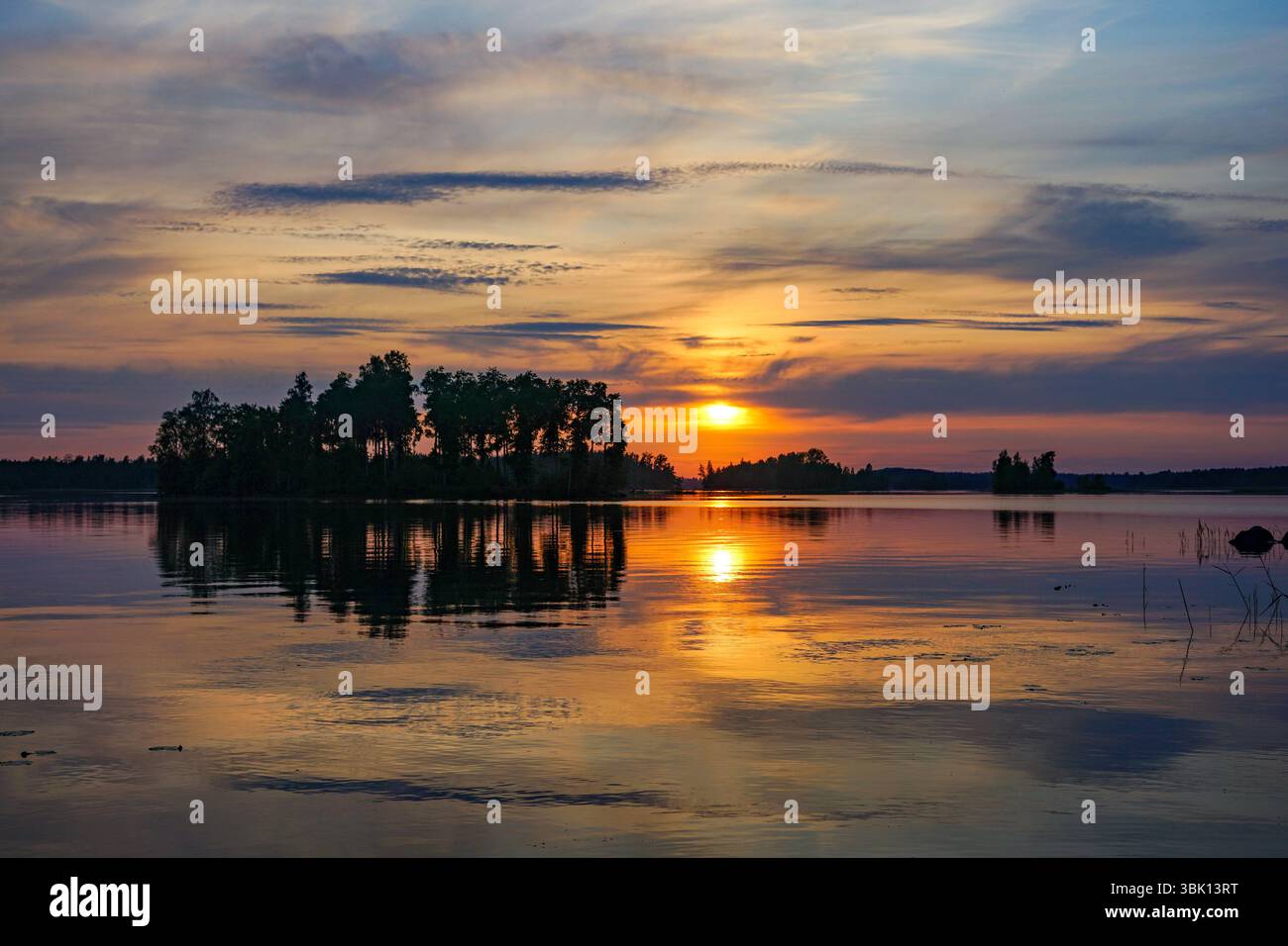 Sonnenuntergang über einem ruhigen See, der die leuchtenden Farben des Himmels reflektiert Stockfoto