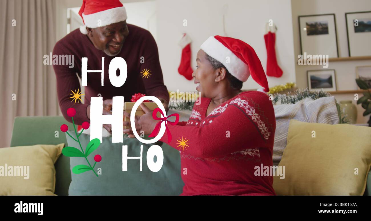 Ein Mann mit Weihnachtsmann, der der Frau auf dem Sofa im Wohnzimmer ein Geschenk mit Band gibt, mit Strümpfen und Tönung Stockfoto