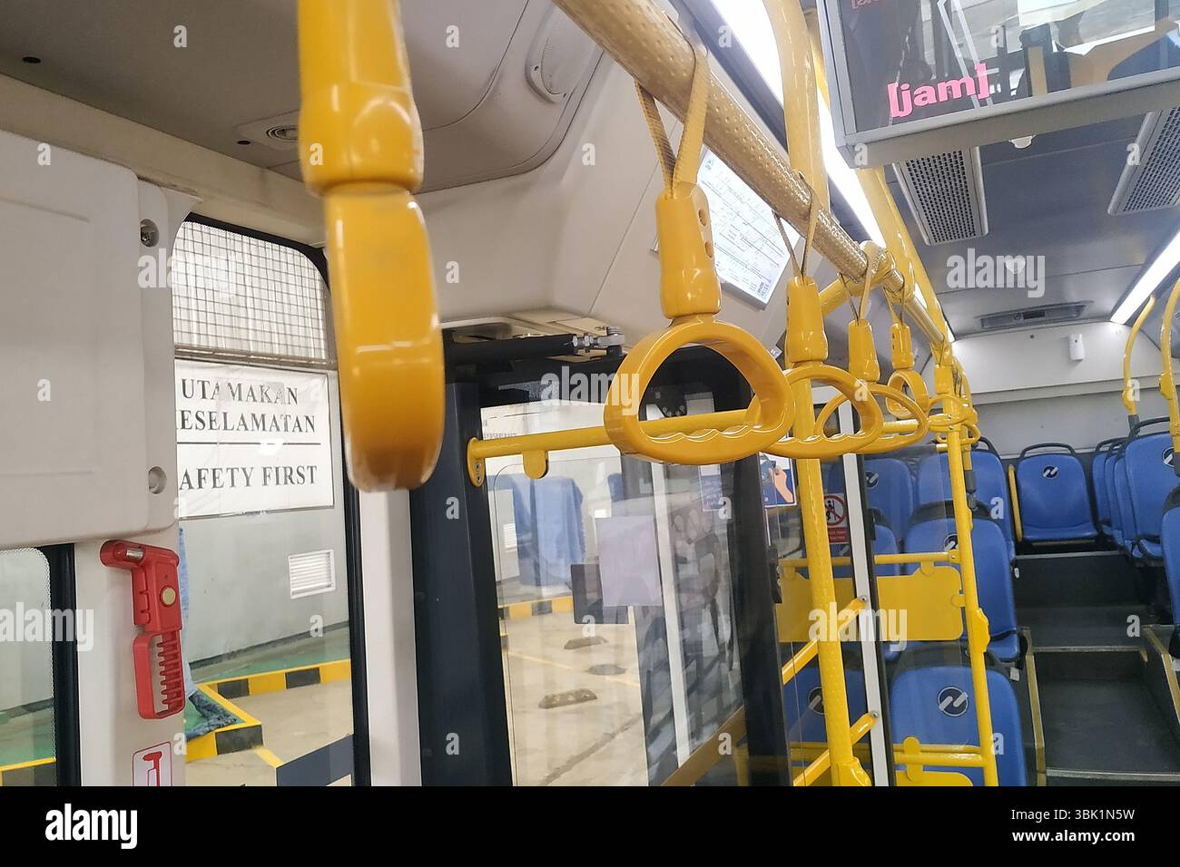 Innenansicht eines modernen elektrischen Stadtbusses mit sauberen, organisierten Sitzgelegenheiten und barrierefreien Merkmalen. Hellgelbe Stangen und kontrastierender Sitz Stockfoto