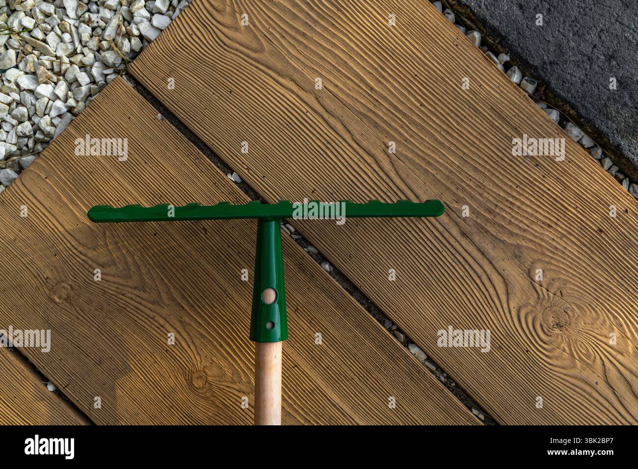 Neue grüne Rechen zum Harken von Blättern auf dem Grundstück auf den Fliesen vor dem Hauseingang Stockfoto