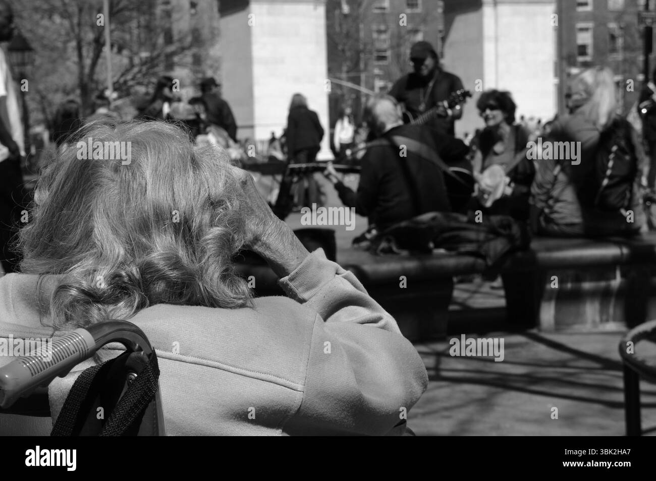 Washington Square Park, eine ältere Frau sieht sich eine Straßenaufführung an. Dieser Moment fängt das Wesen der Gemeinschaft und der generationenübergreifenden Verbindung ein. Stockfoto