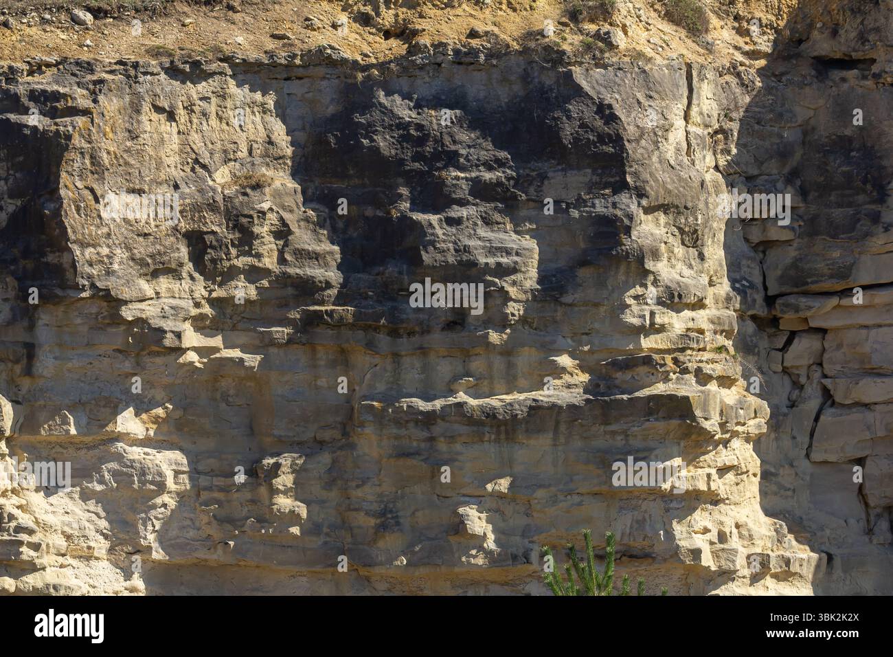 Mehrere geologische Gesteinsschichten sind in einer zerklüfteten Landschaft sichtbar, die unterschiedliche Texturen und Muster hervorheben, die durch Verwitterung und Erosion in br geformt wurden Stockfoto