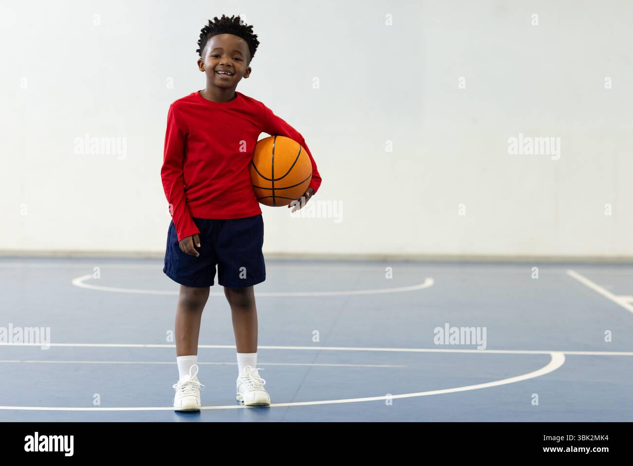 afroamerikanischer Junge, der Basketball auf dem Platz hält, Sportaktivitäten in der Schule genießt, Kopierraum Stockfoto