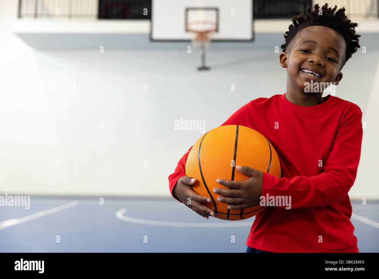 Lächelnder afroamerikanischer Junge, der Basketball in der Schule hält, Sport genießt, Kopierraum Stockfoto