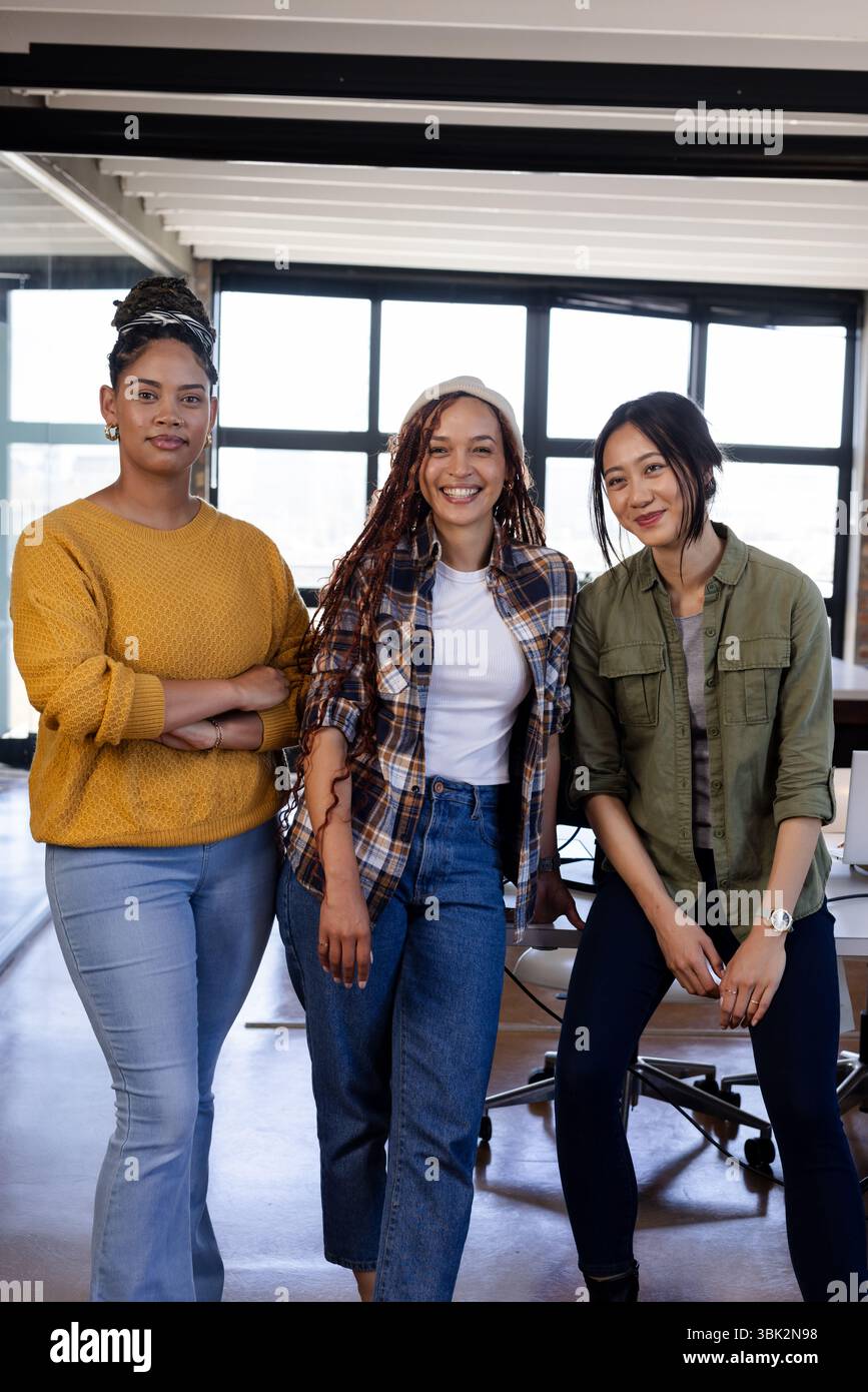 Selbstbewusste, vielseitige Frauen in Freizeitkleidung, die in modernen Büroräumen zusammenarbeiten Stockfoto