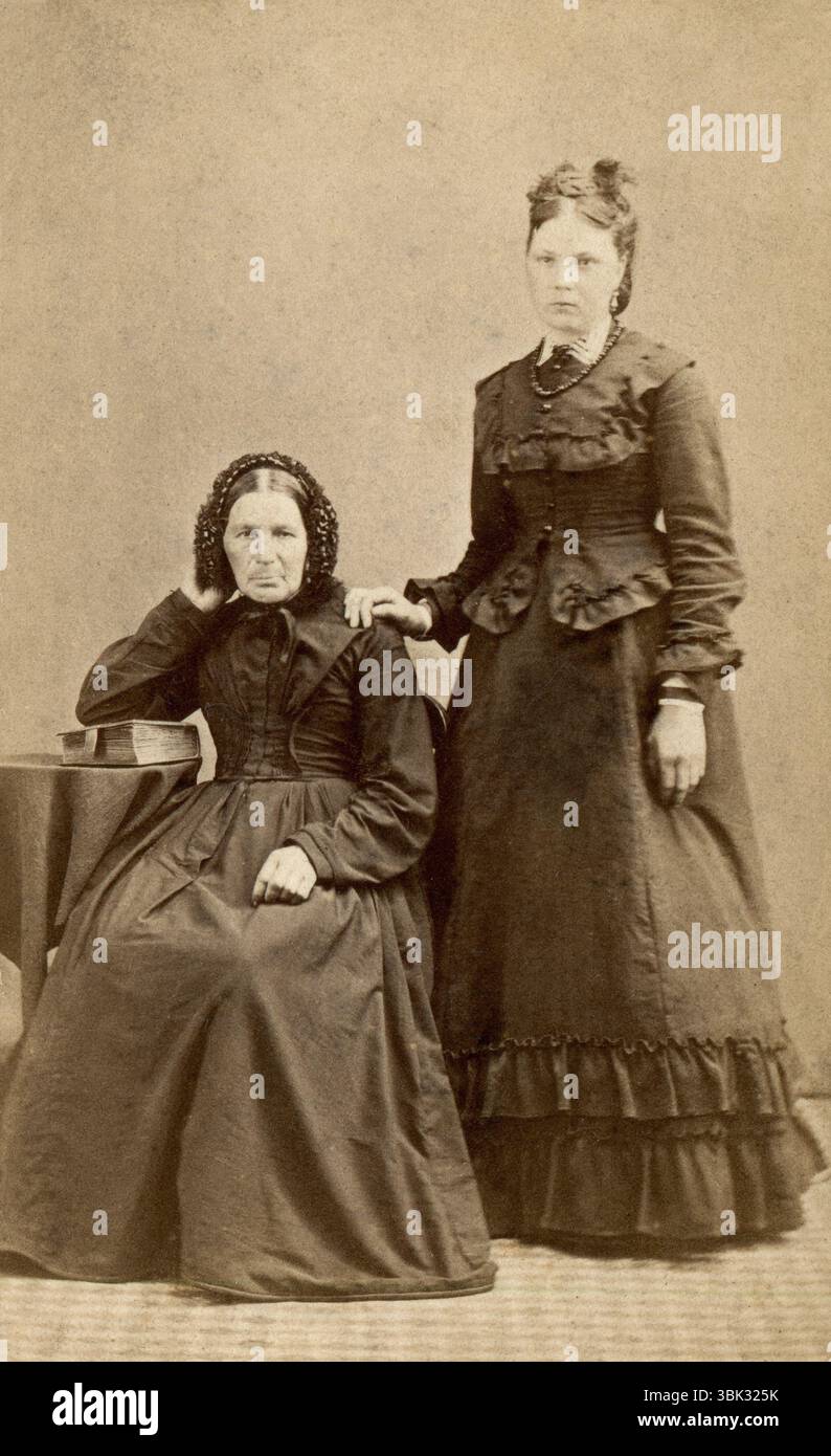 Hertfordshire, England. Um 1870 – Ein Atelierporträt Carte de Visite Foto von Sarah Drage (1814–1888) und ihrer Tochter Rose Esther Drage (1857–1905) aus Royston, Hertfordshire. Aufgenommen um 1870 vom Fotografen William Norman aus der High Street, Royston. Sarah sitzt mit dem Ellenbogen auf einer Bibel, und Rose steht mit der Hand auf der Schulter ihrer Mutter. Stockfoto