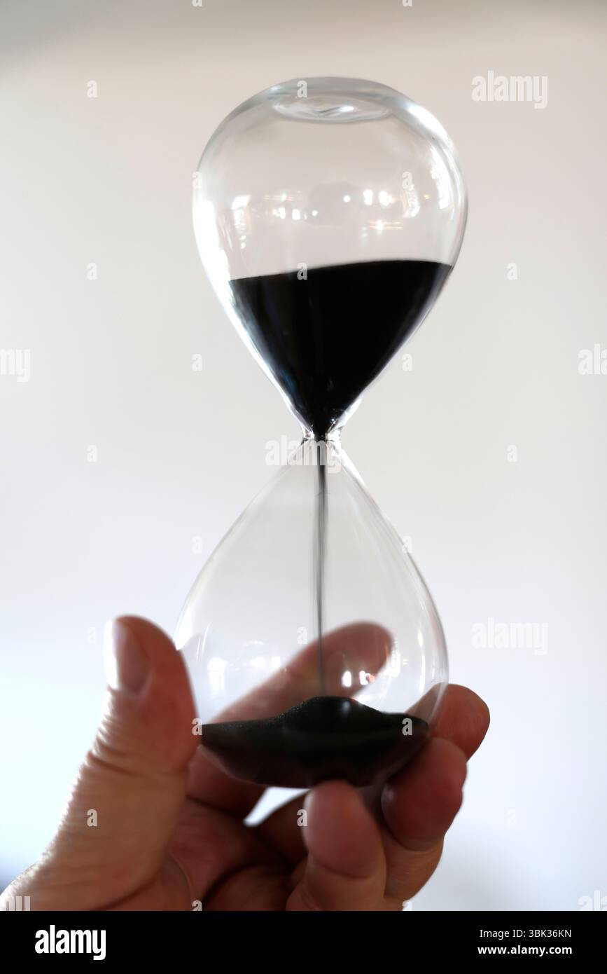 Sanduhr mit ablaufender Zeit in der Hand. Konzept des Zeitverlaufs. Stockfoto