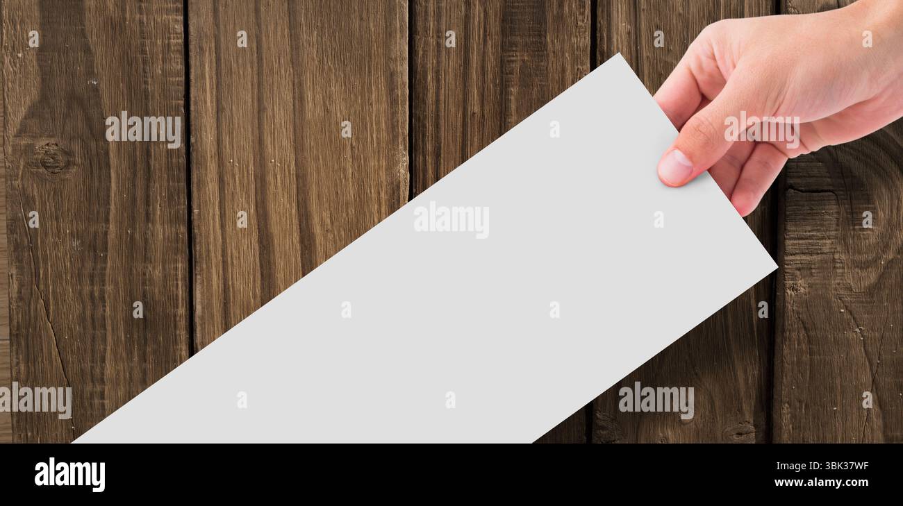 Die rechte Hand hält leeres weißes Papier schräg gegen den Hintergrund einer Holzdiele in flacher Ausführung Stockfoto Die rechte Hand hält leeres weißes Papier schräg gegen den Hintergrund einer Holzdiele in flacher Ausführung Stockfoto