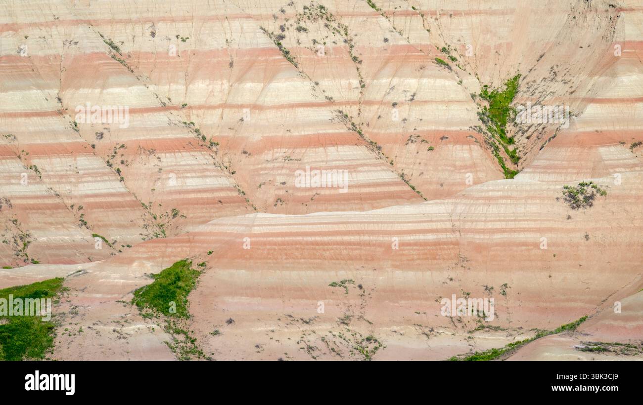 Felsformationen mit farbenfrohen Mustern und Gras im Badlands-Nationalpark, South Dakota, USA. Stockfoto