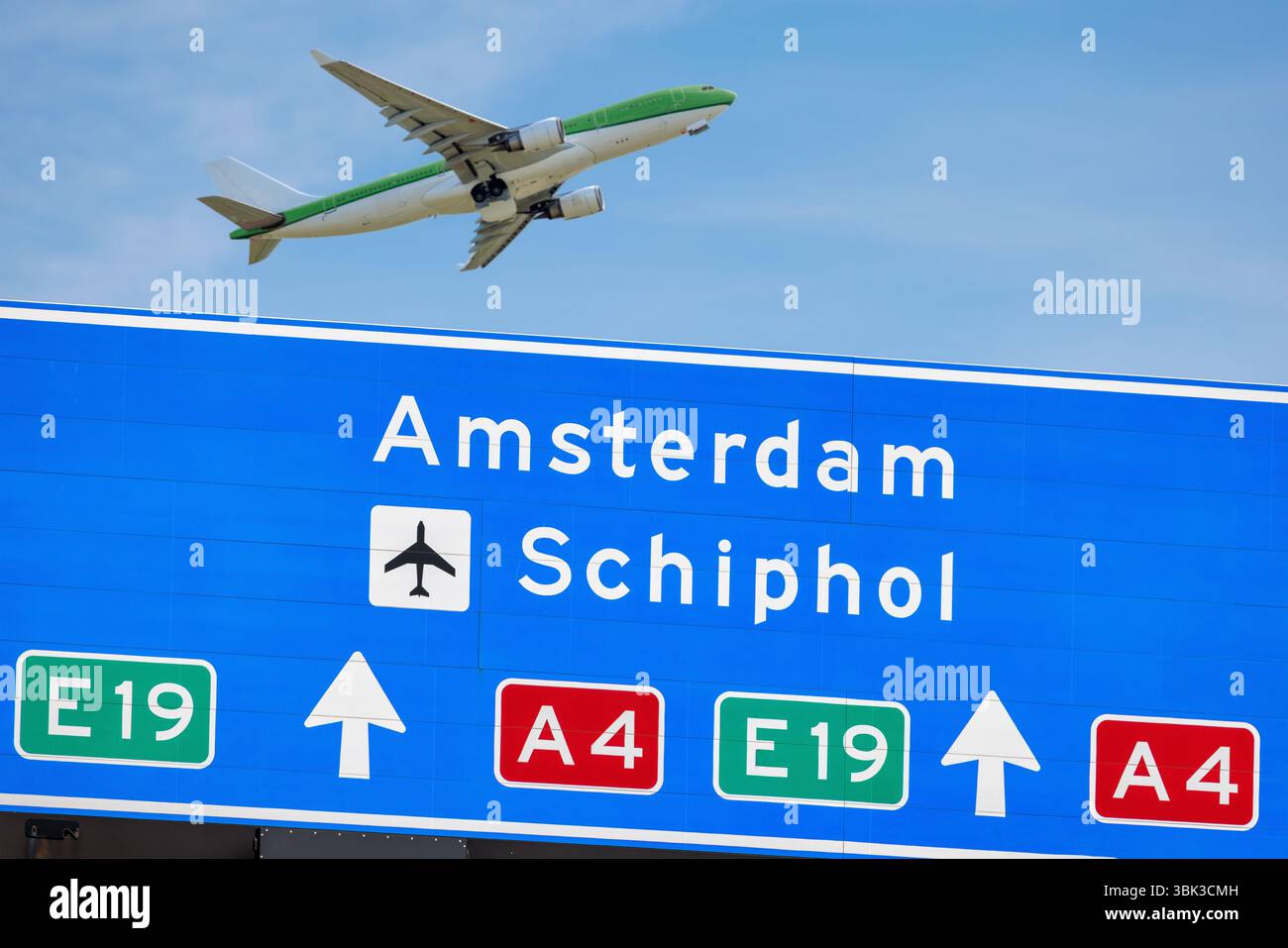 Holländisches Straßenverkehrsschild nach Amsterdam und Schiphol Flughafen mit Passagierflugzeug im Hintergrund Stockfoto