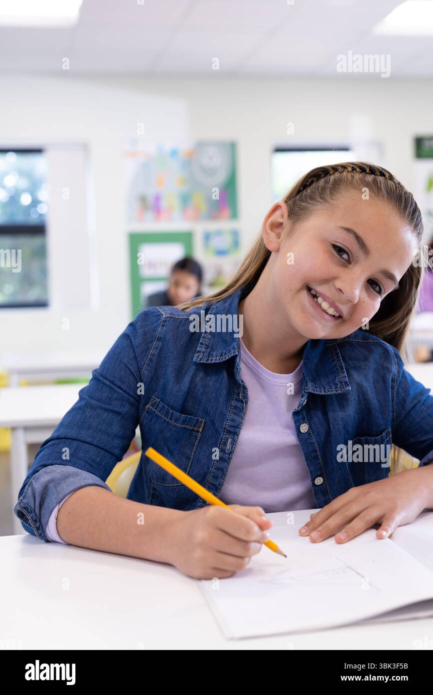 Lächelndes Mädchen zeichnet im Klassenzimmer und genießt kreative Aktivitäten in der Schule Stockfoto