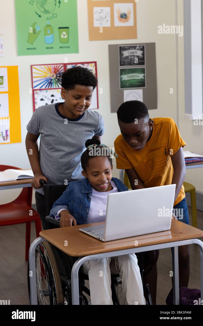 Verschiedene Schüler im Klassenzimmer treffen sich um Laptop und arbeiten an Schulprojekten zusammen Stockfoto