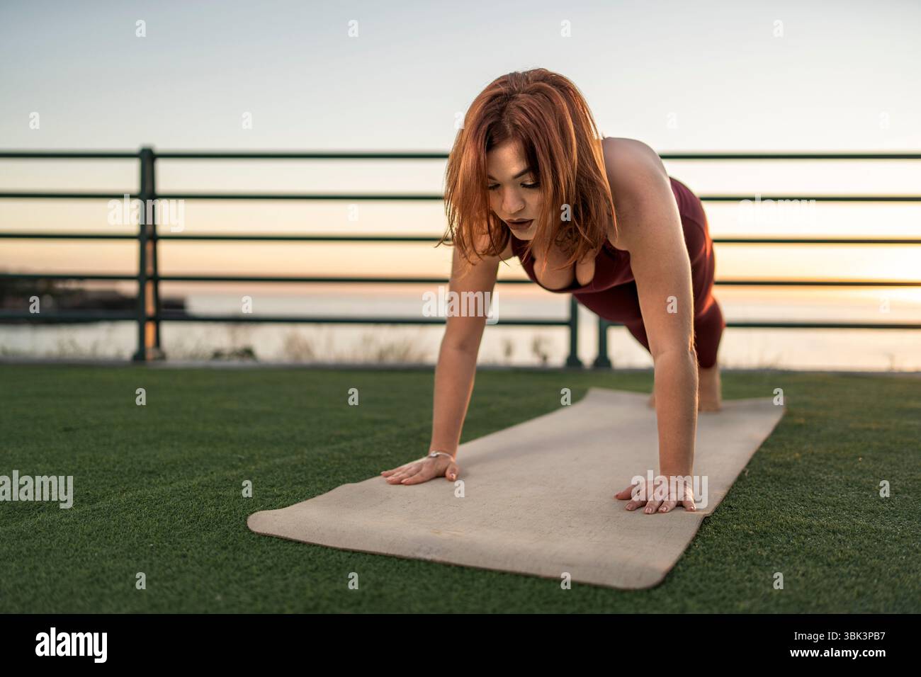 Eine junge Sportfrau in Sportbekleidung macht eine erfrischende Pause und trinkt ein Getränk aus der Dose, während sie nach einem Workout draußen sitzt. Ein Hyd-Konzept Stockfoto