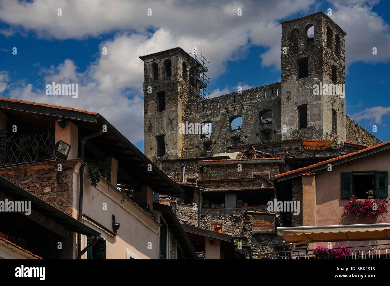 Narben der Schlacht: Renaissance-Fresken auf dem quadratischen Turm aus dem 16. Jahrhundert der Ruine der mittelalterlichen Burg Doria oder Castello dei Doria in Dolceacqua, Ligurien, Italien, gespickt mit Löchern, die 1744 von französisch-spanischen Kanonenkugeln hinterlassen wurden. Die Festung aus dem 12. Jahrhundert, die hier repariert wurde, war die Heimat der Doria-Herrscher von Genua. 1884 malte der französische Impressionist Claude Monet die Burg und die nahe gelegene Ponte Vecchio, die den Fluss Nervia überspannte. Stockfoto
