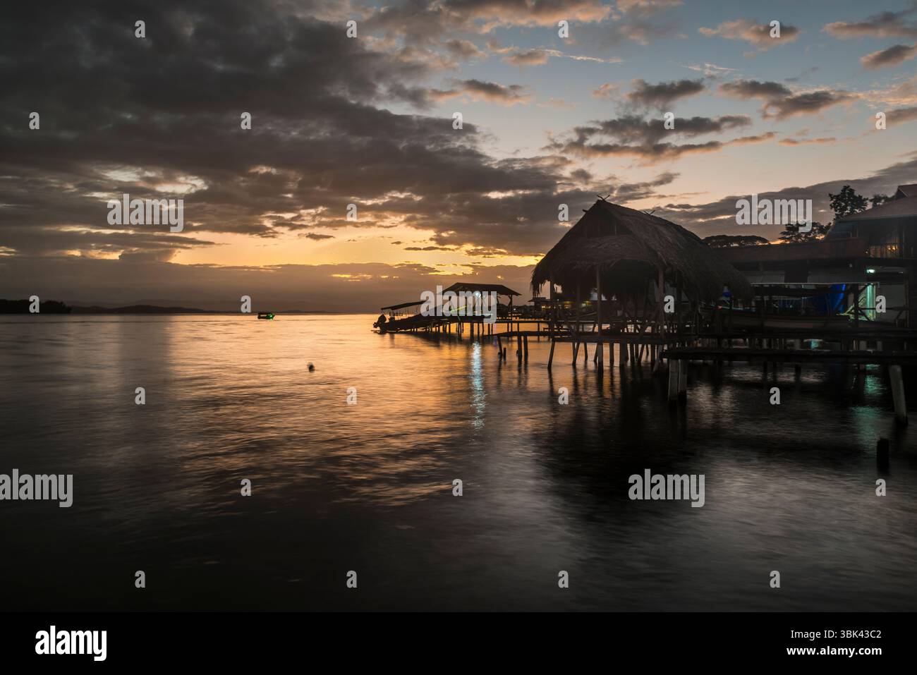 Blick bei Sonnenuntergang auf Pfahlhäuser und ein verankertes Boot in Old Bank Town, Isla Bastimentos, Bocas del Toro, Panama Stockfoto