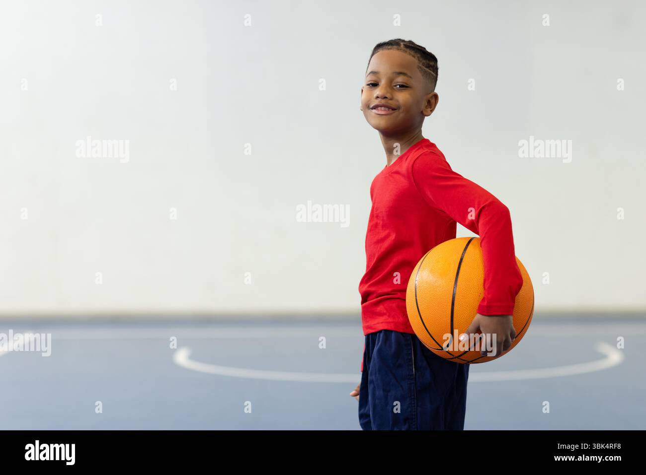 Lächelnder Junge, der Basketball auf dem Platz hält, Schulsport genießt, Kopierraum Stockfoto