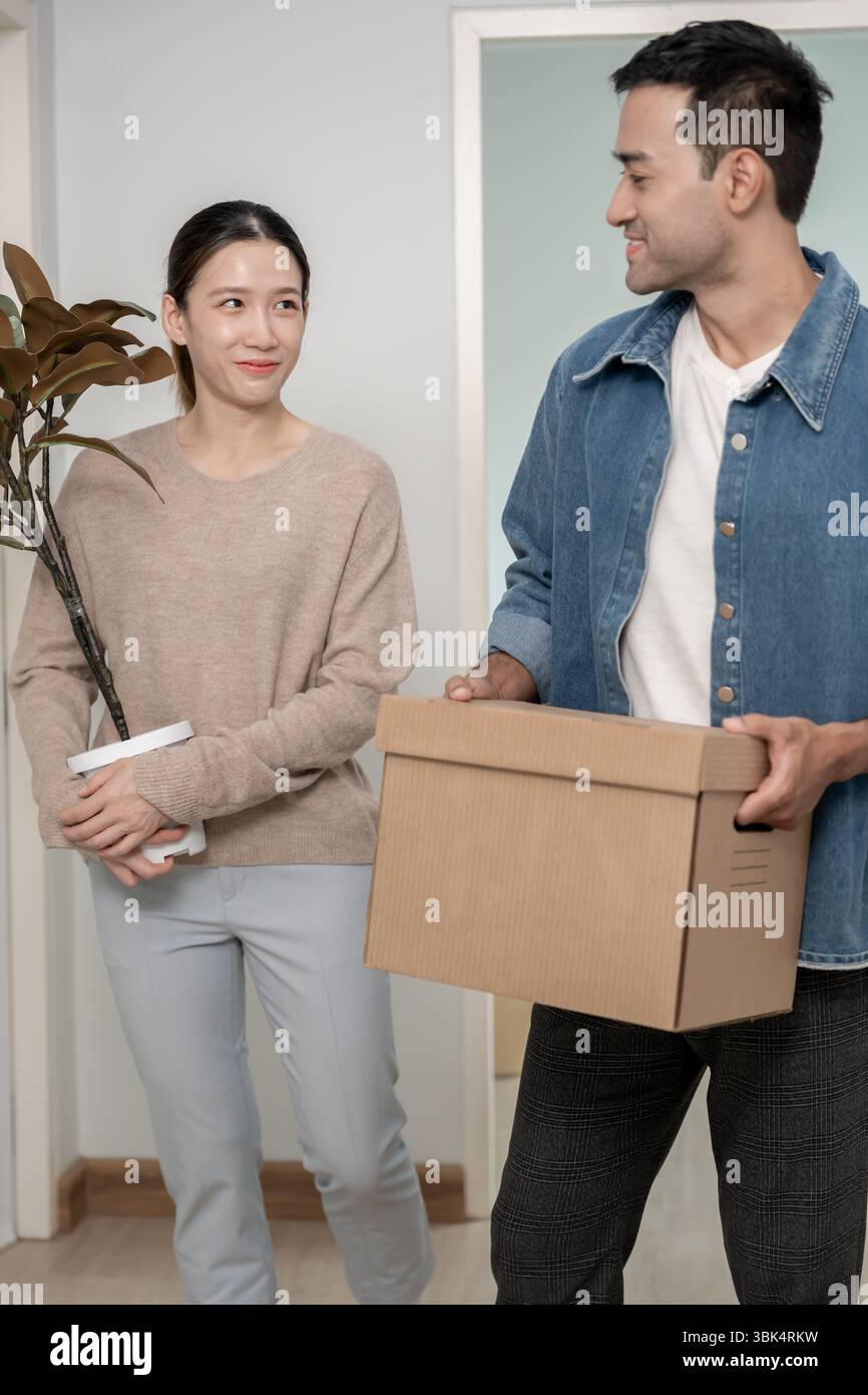 Umzugshaus, Ehemann und Ehefrau halten Box und Möbel für eine neue Wohnung oder ein neues Zuhause, im Zimmer war eine Pappschachtel mit persönlichen Sachen und Stockfoto