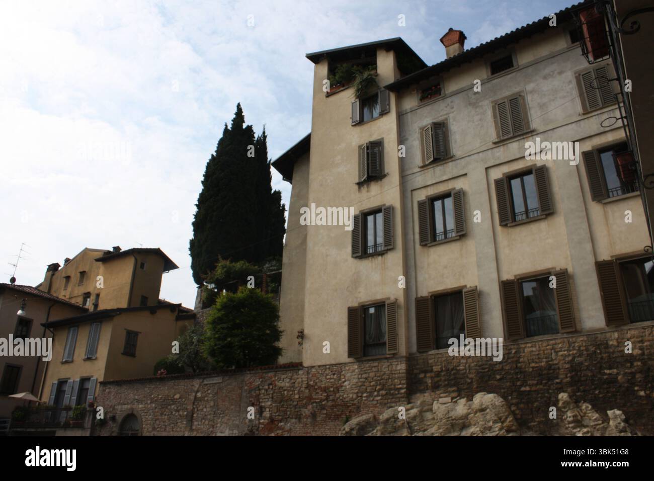 Italienische Architektur in Bergamo mit hellen und warmen Gebäuden. Rollläden und Zypressen Stockfoto