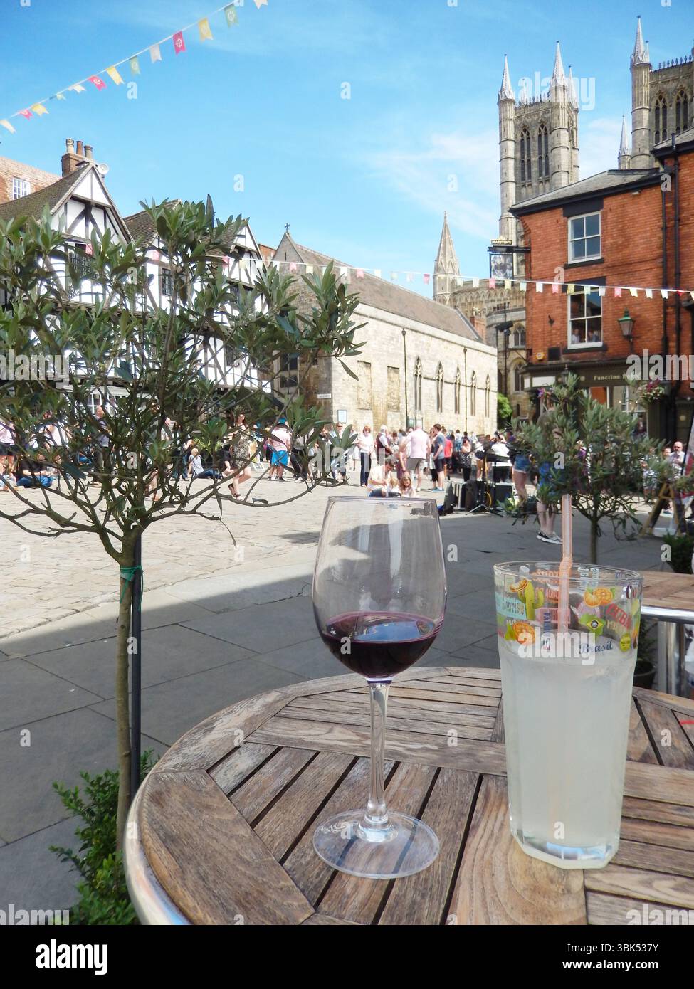 Café-Tisch im Freien mit Getränken und Blick auf historische Architektur und Flaggendekoration. Lincoln, England Stockfoto