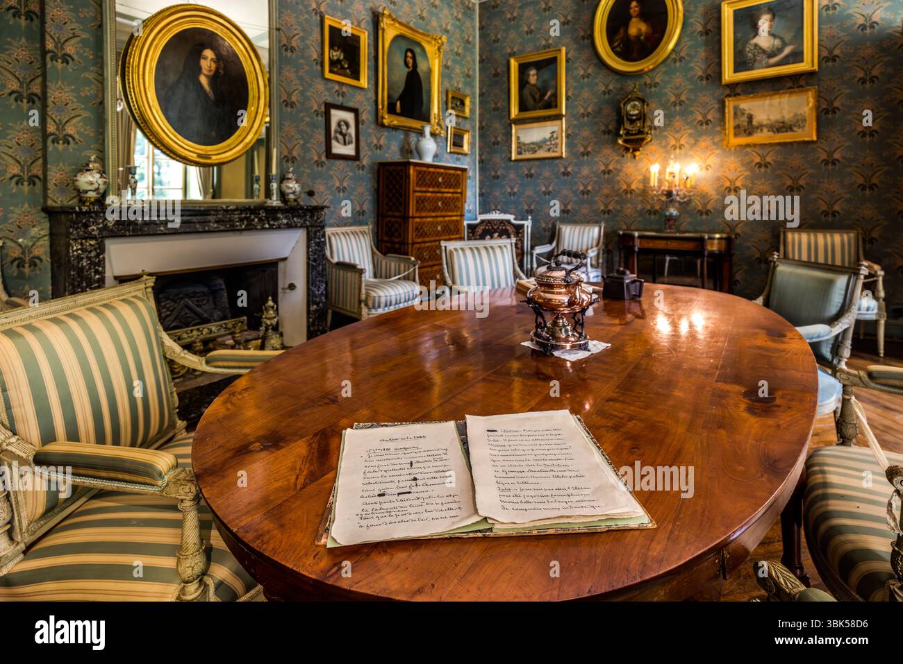 Salon in George Sands Haus in Nohant mit Porträts ihrer Vorfahren und Nachkommen. Das Anwesen Nohant ist noch immer untrennbar mit George Sand verbunden und mit vielen Originalstücken ausgestattet. Die meisten ihrer Werke (Romane, Märchen, Geschichten, Theaterstücke, Rezensionen, politische Artikel, autobiografische Texte und Briefe) wurden in Nohant geschrieben. Ab 1835 wurde George Sand politisch aktiv und kämpfte für sozialen Fortschritt und gleiche Rechte für Frauen. Über dem Kamin hängt das berühmte Porträt von George Sand von Auguste Charpentier aus dem Jahr 1838. Place Sainte Anne, Nohant-Vic, Centre-Val de Stockfoto