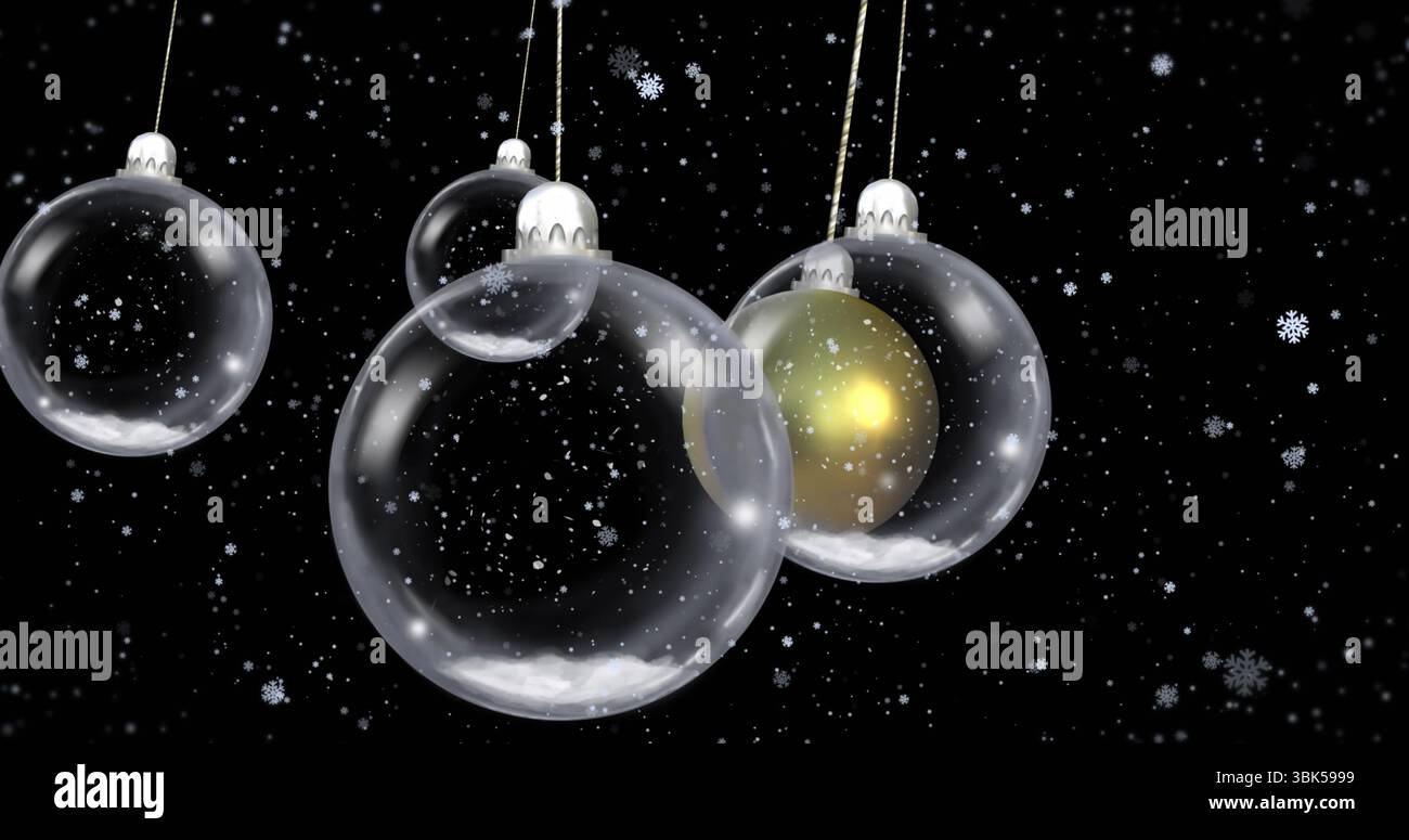 Glaskugeln hängen an Metallkappen am dunklen Himmel mit leuchtender goldener Kugel und fallenden Schneeflocken Stockfoto