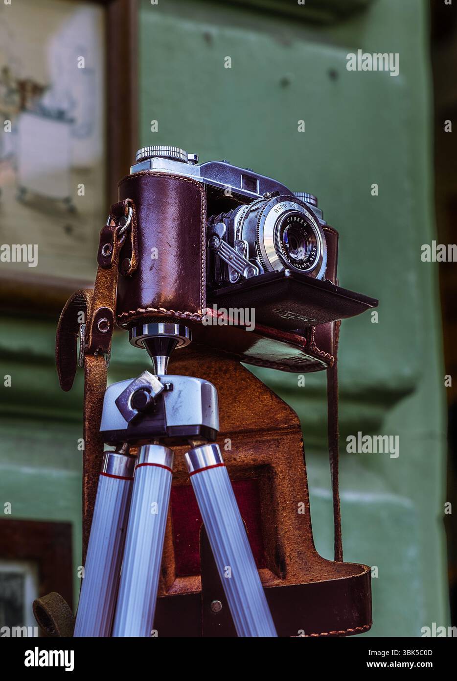 Eine Vintage-Kamera, die wunderschön in ihrer Ledertasche aufbewahrt und auf einem klassischen Stativ montiert ist, hält zeitlose Momente fest. Stockfoto