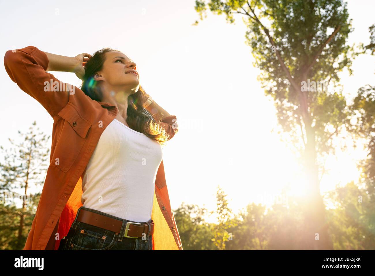 Stadtfrau mit Händen hinter Kopf, die sich nach der Arbeit im Stadtpark entspannt. Vereinbarkeit von Beruf und Privatleben. Psychische Gesundheit und Erholung. Stockfoto