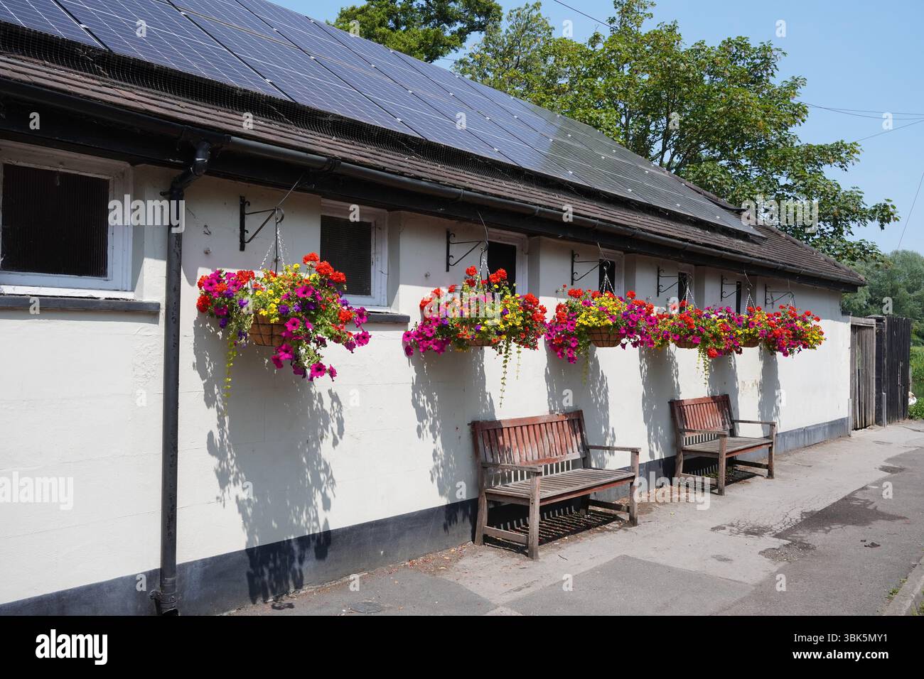 Äußere des traditionellen englischen Pubs mit hängenden Blumenkörben zur Dekoration. Malerisches Wirtshaus im Dorf Stockfoto