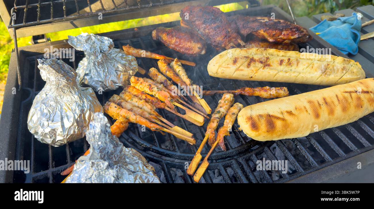 Gegrilltes Fleisch und Garnelenspieße mit Baguettes auf dem Grill im Garten Stockfoto