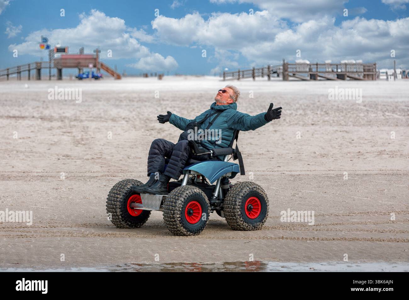 Behinderter Mann im Strandrollstuhl, hebt die Arme vor Freude, Sankt-Peter-Ording, Schleswig-Hostein, Deutschland, Europa Stockfoto