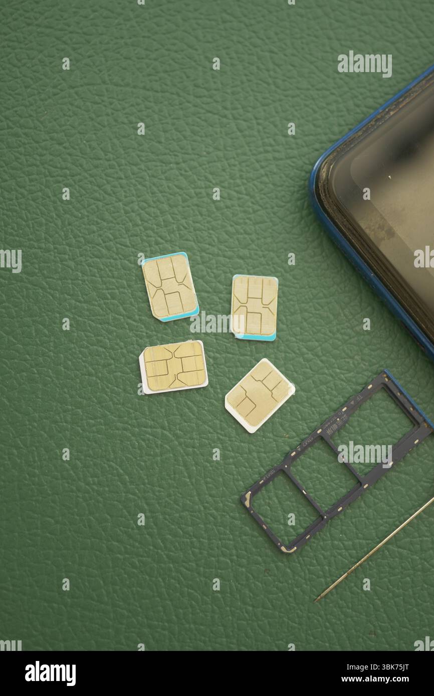 Mehrere SIM-Karten und ein Smartphone auf grüner Oberfläche Stockfoto
