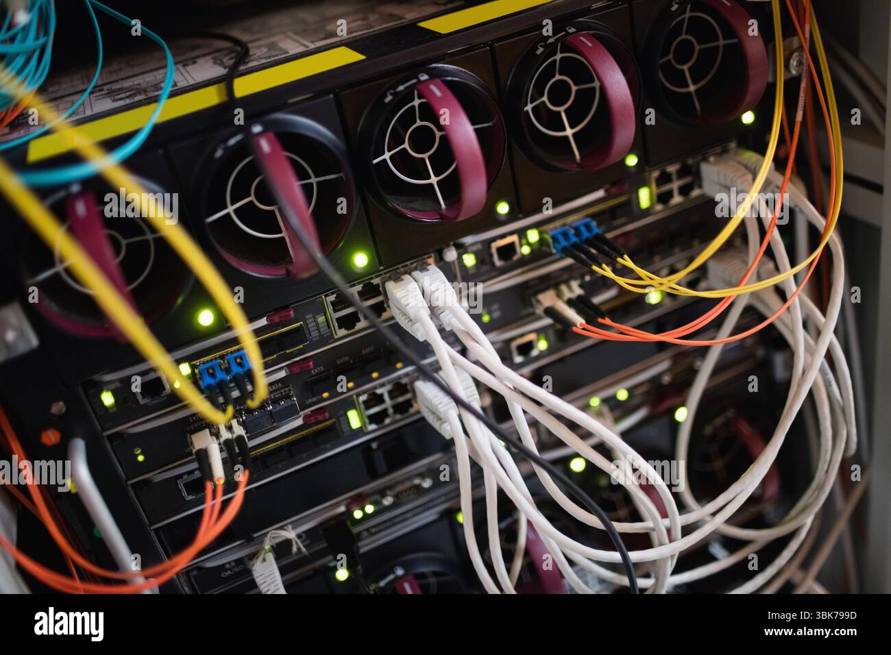 Zeigt ein Nahaufnahme-Rack mit Switches und Routern mit Lüftern mit LED-Leuchten und Kabeln Stockfoto Zeigt ein Nahaufnahme-Rack mit Switches und Routern mit Lüftern mit LED-Leuchten und Kabeln Stockfoto