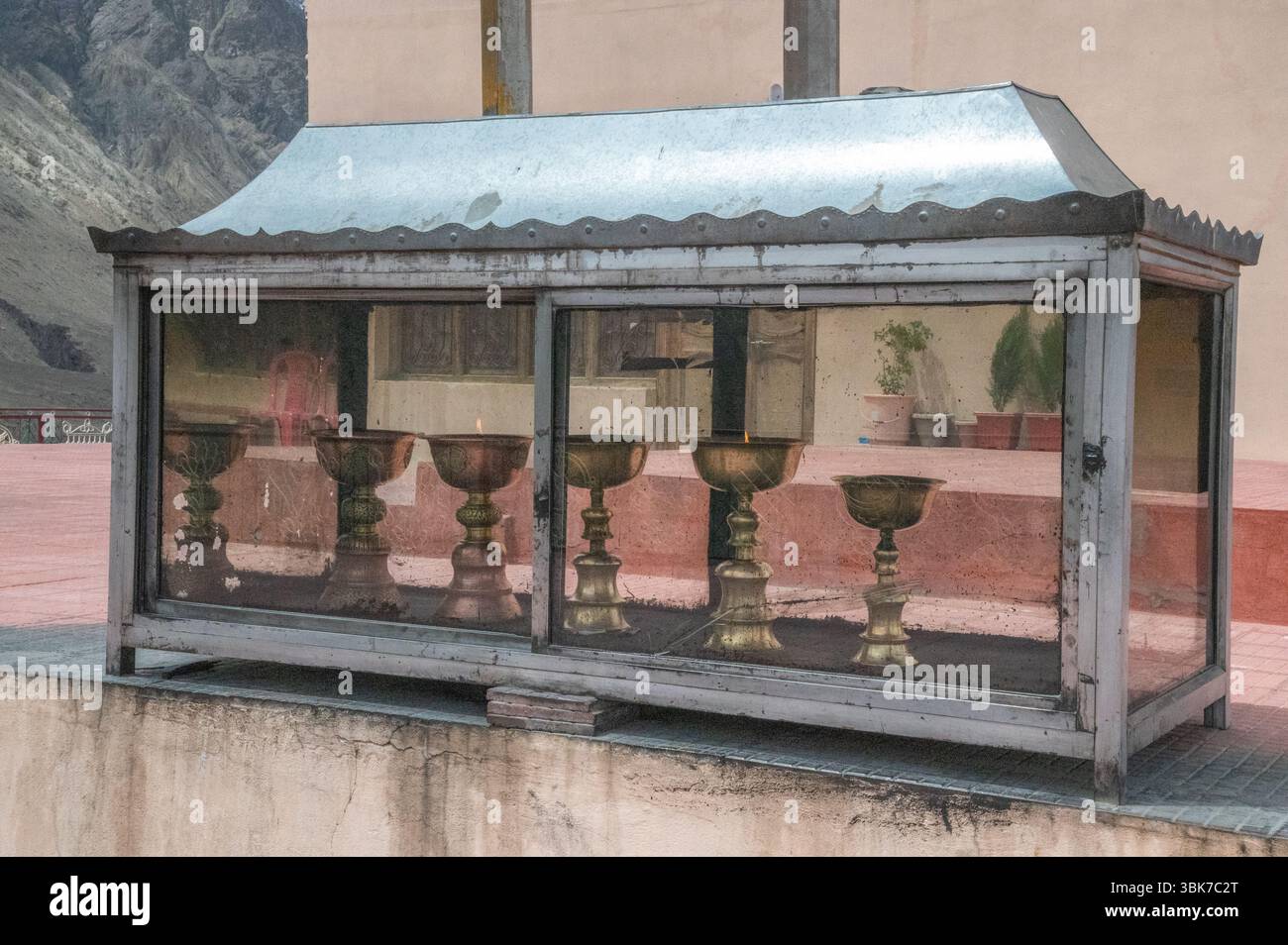 Goldene Gebetslampe vor der Statue des Maitreya Buddha in Diskit, Nubra Valley, Ladakh, Indien, symbolisiert spirituelles Licht und Hingabe. Stockfoto
