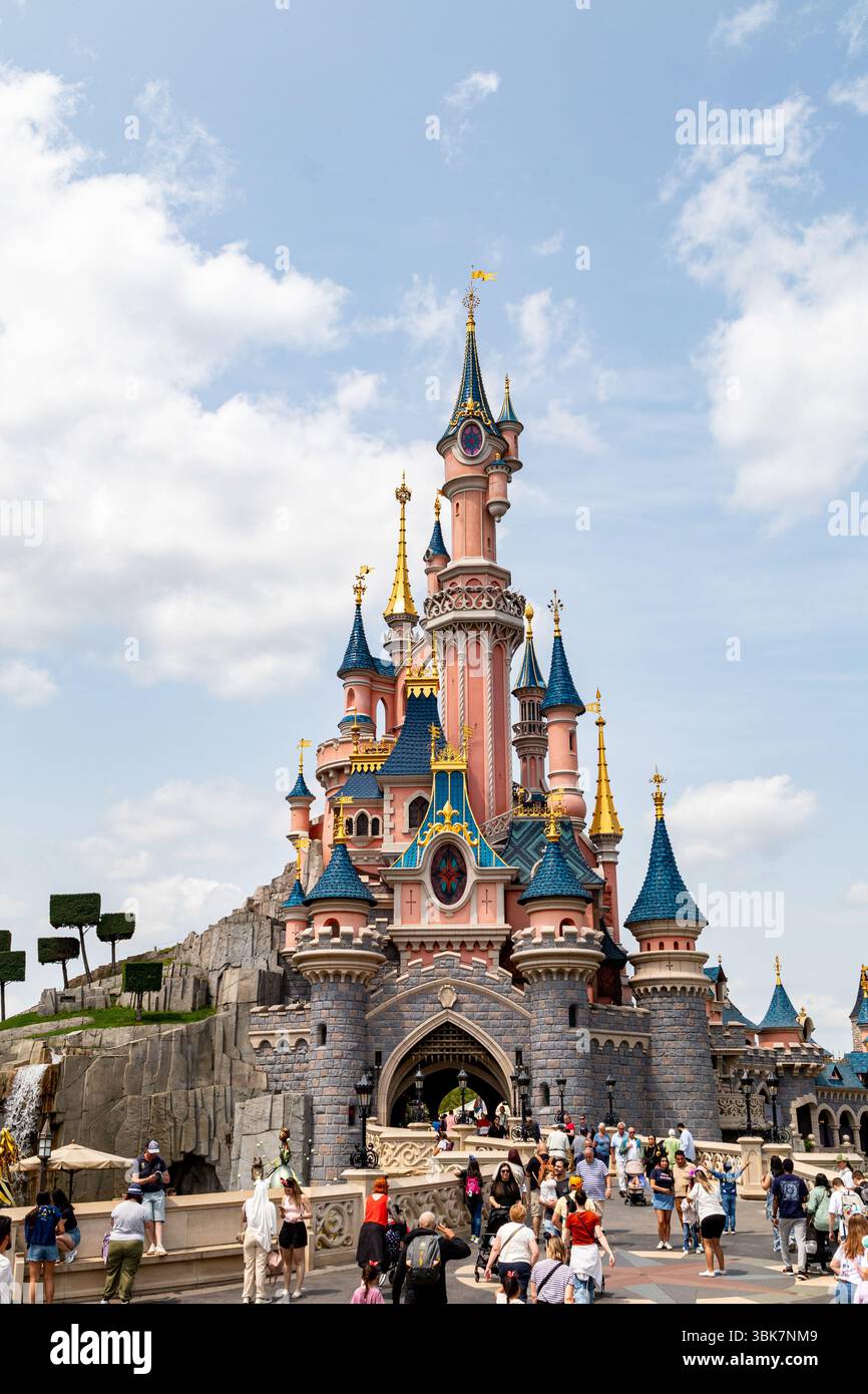 Vollständige Aufnahme des Schlosses von Disneyland Paris, mit einer Menschenmenge vor der Tür und einem blauen Himmel mit Wolken im Hintergrund. Stockfoto