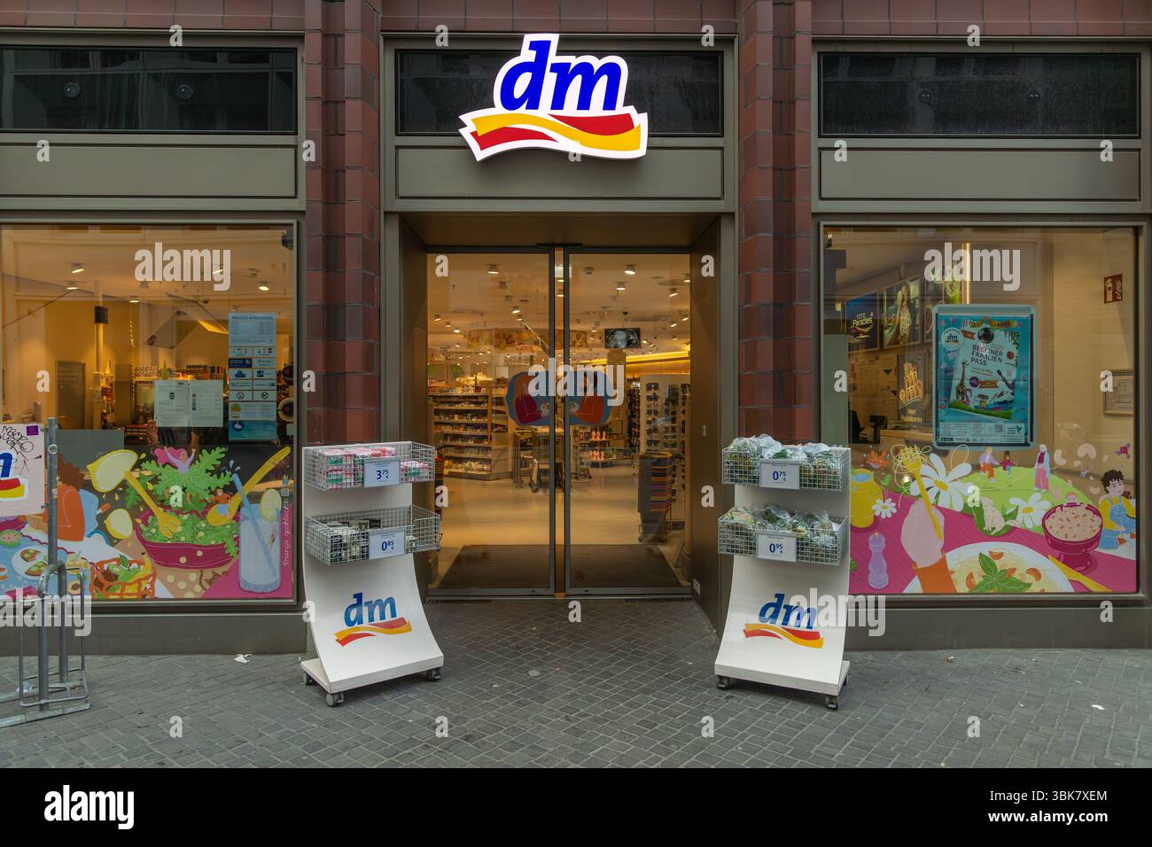 Der Eingang einer dm Drogerie in einer europäischen Stadt lädt mit seinem hellen Logo und Schaufensterdisplays zum Einkaufen ein. Berlin, Deutschland. 29. März 2025. Stockfoto
