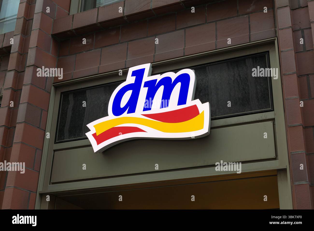 Ein hell beleuchtetes dm (drogerie markt)-Logo-Schild an einer Gebäudefassade weist auf eine Drogerie in einer europäischen Stadt hin. Berlin, Deutschland. 29. März 2025. Stockfoto