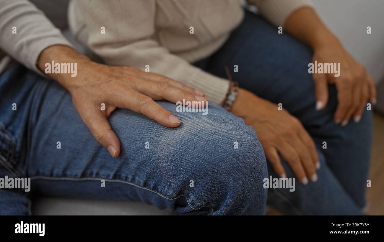 Paare mittleren Alters, die zu Hause auf der Couch sitzen und Liebe und Zweisamkeit in einem gemütlichen Wohnzimmer zeigen, was intime Momente älterer Männer hervorhebt Stockfoto
