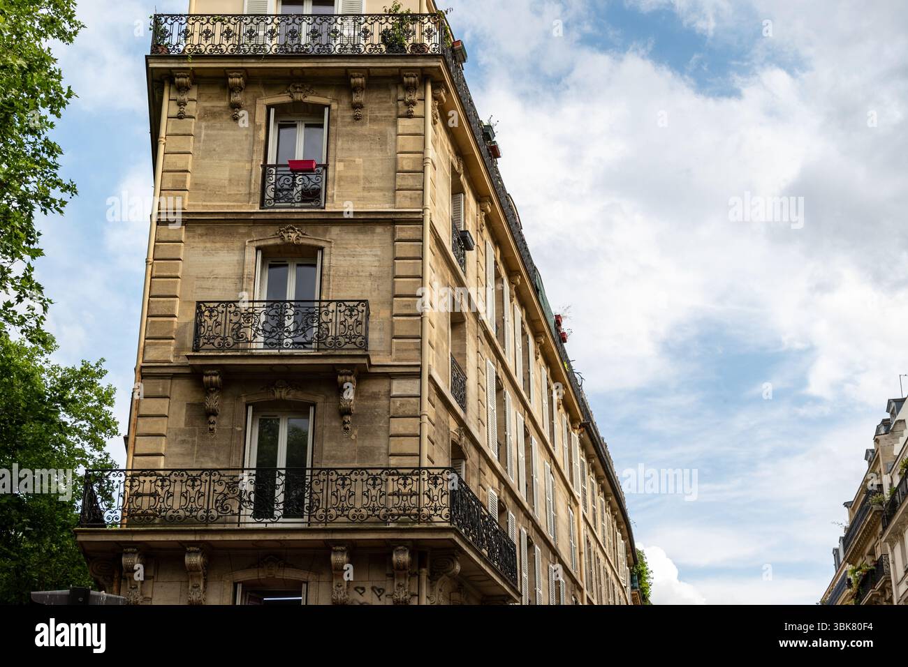 Ein flaches Bild eines Pariser Gebäudes mit ornamentalen Balkonen, Fenstern und architektonischen Details vor einem bewölkten Himmel. Stockfoto