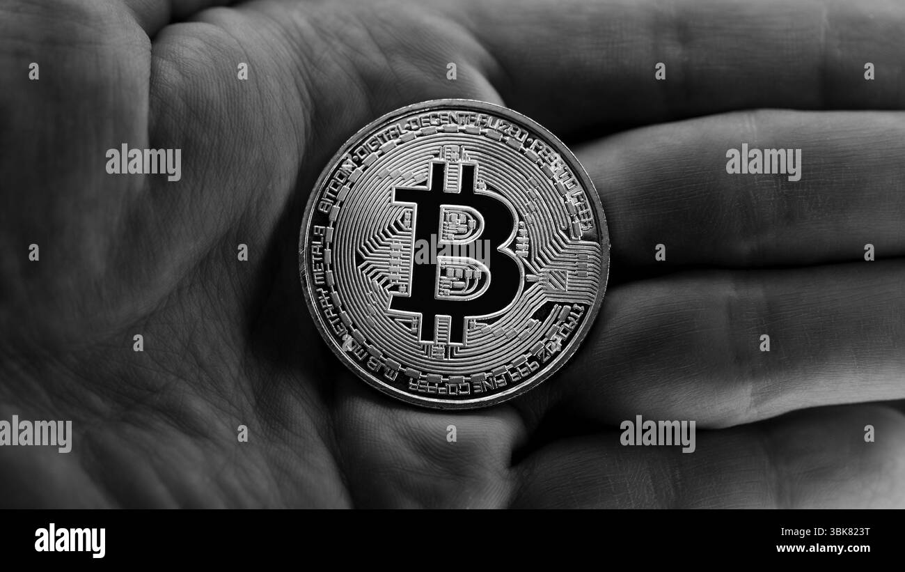 Physisches Bitcoin in Händen, Nahaufnahme Foto in Schwarzweiß Stockfoto