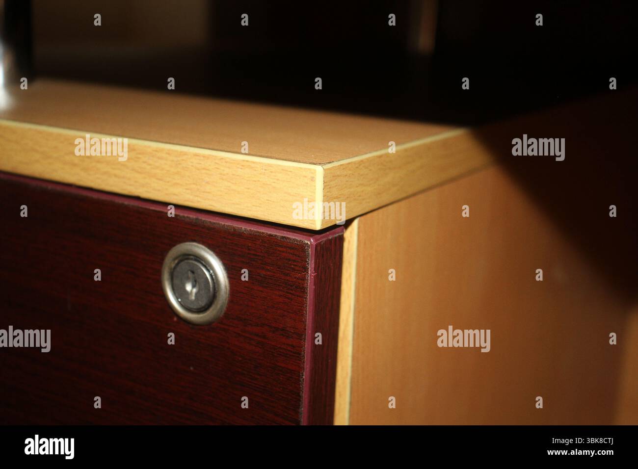 Nahansicht einer hölzernen Schubladenecke mit integriertem Metallschloss. Die Schublade verfügt über eine satte, dunkle Oberfläche auf der Vorderseite. Stockfoto